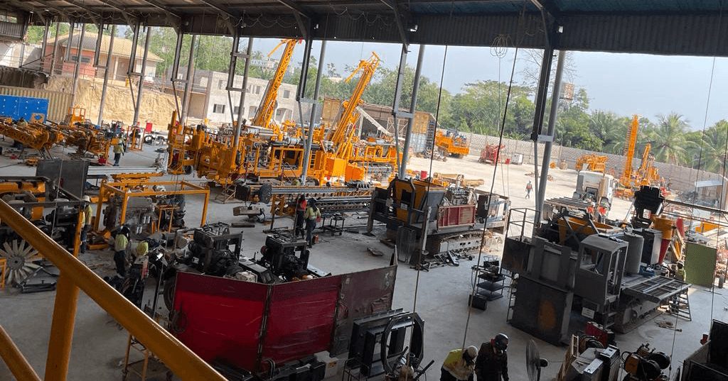 A fabrication yard with heavy machinery being assembled under a steel roof.
